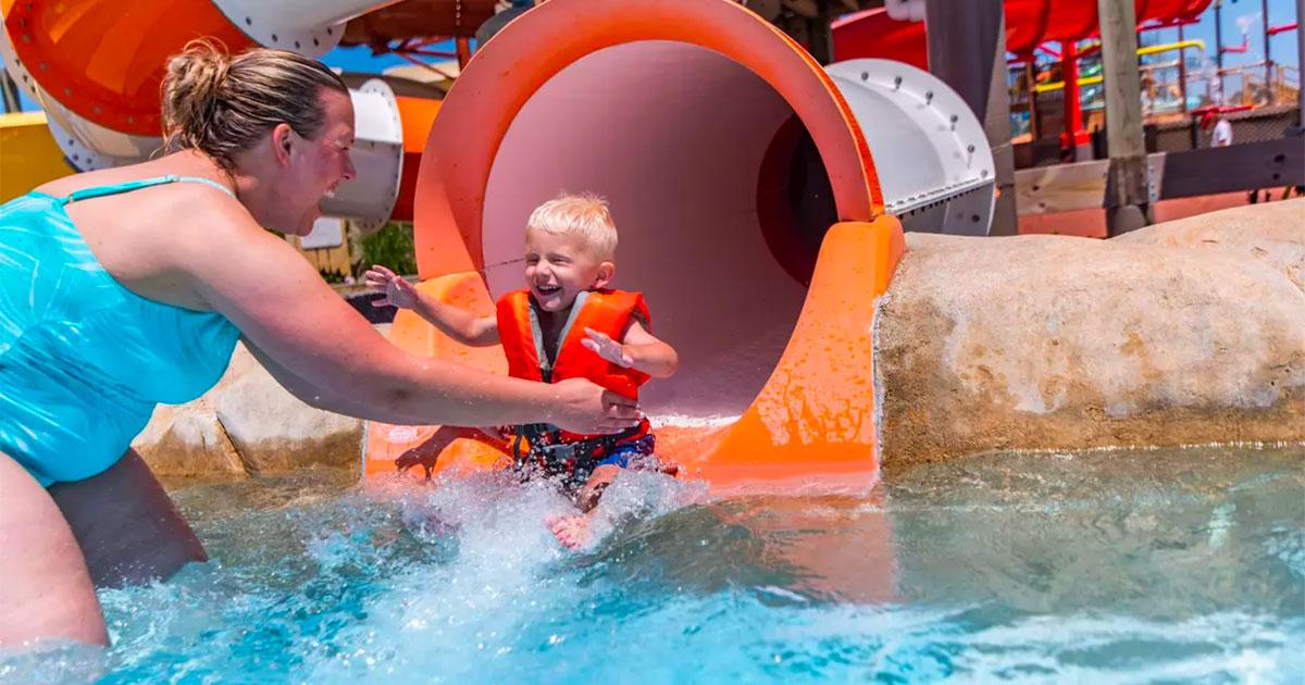 Mom grabbing son out of orange and white slide