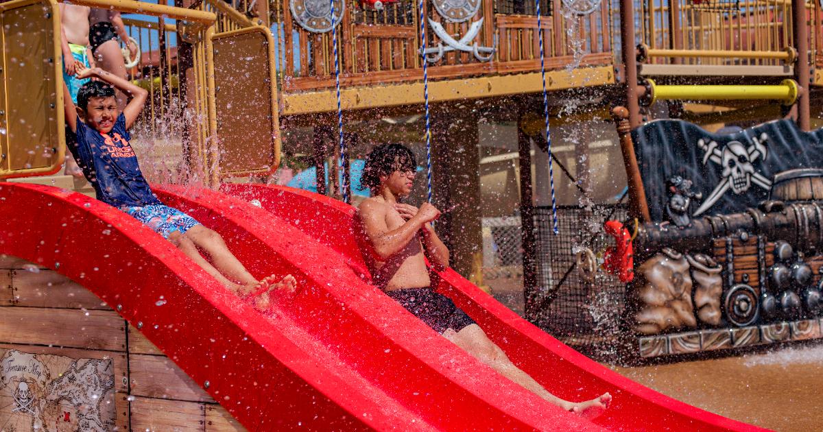 Boys sliding on red slide