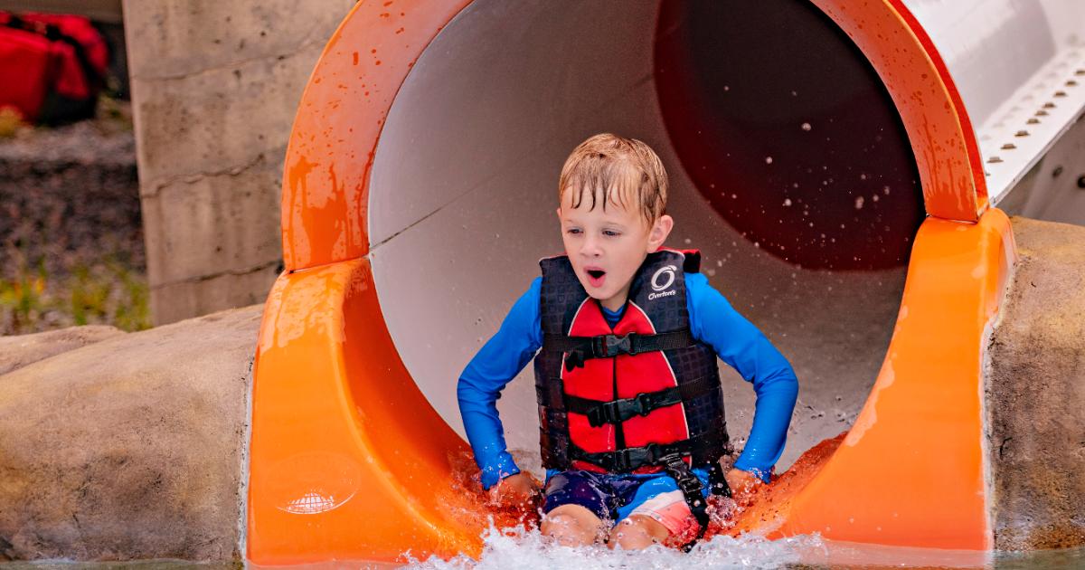 kid in lifejacket coming out of slide